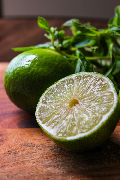 Free Close-up of fresh lime and mint leaves on a wooden surface, perfect for culinary use. Stock Photo