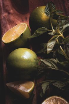 Close-up of fresh limes and mint leaves on a wooden surface, ideal for culinary themes.