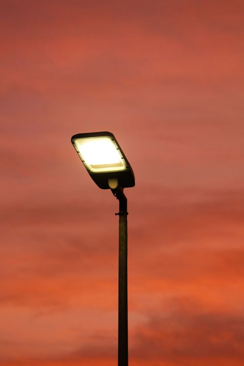 Free A silhouetted street lamp glows against a vibrant, dramatic sunset sky in Madinah, Saudi Arabia. Stock Photo