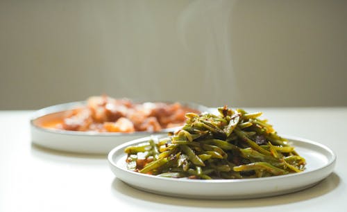 Free Steaming Green Beans and Stew on White Plates Stock Photo