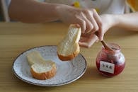 A Close-Up Shot of a Person Eating Bread and Jam