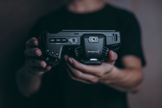 Detailed close-up of a person's hands holding a modern camera device.