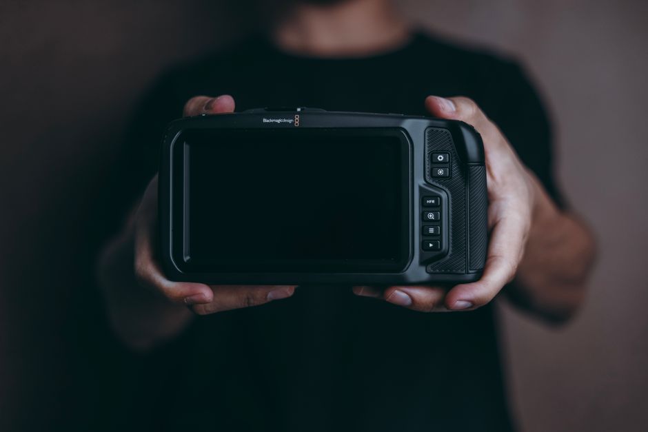 A person holding a modern digital camera in a close-up view. Perfect for tech and photography themes.