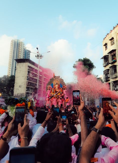 Crowd celebrating Ganesh Chaturthi in Mumbai with vibrant colors and large idol.