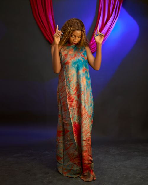 Free A woman poses in a colorful tie-dye dress against a dramatic backdrop. Stock Photo