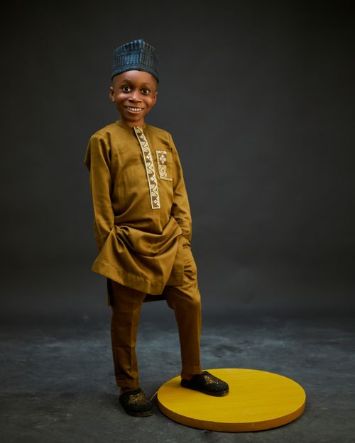 Free Smiling boy in brown traditional outfit with a playful pose on a studio backdrop. Stock Photo