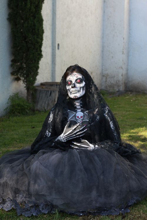 Free Person in elaborate skeleton costume, seated outdoors, inspired by Day of the Dead. Stock Photo