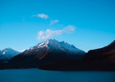 A breathtaking view of snow-covered mountains with clear blue sky at dawn.