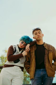 Stylish young adults posing outdoors with laid-back expressions and unique fashion.