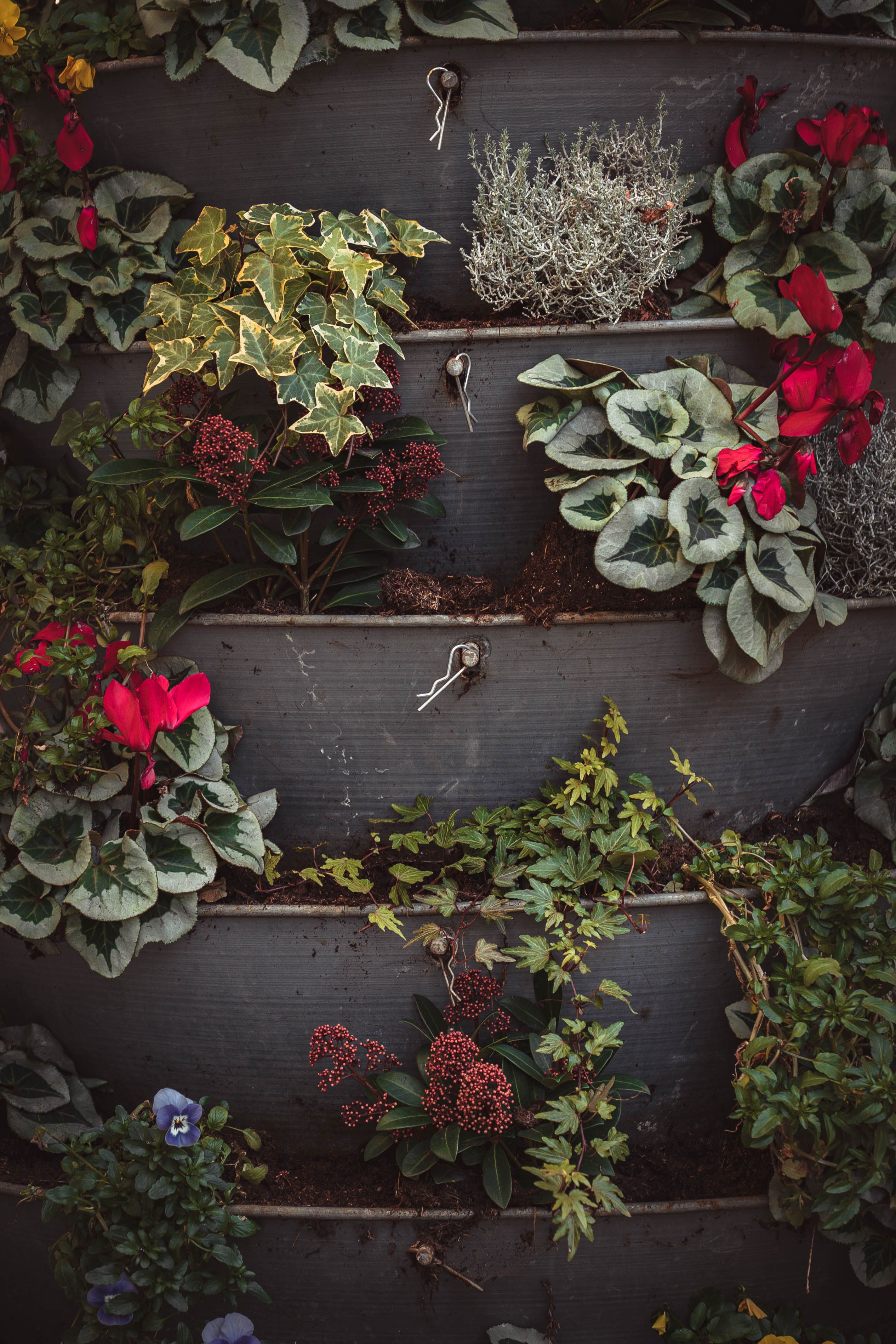 Three-tier ceramic vertical planter on a small apartment patio, holding herbs and small flowering plants