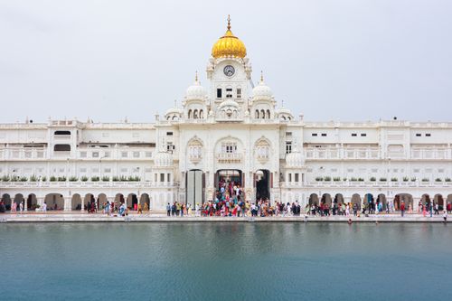 Free A serene view of the Golden Temple in Amritsar with its iconic gold dome and reflective pool. Stock Photo