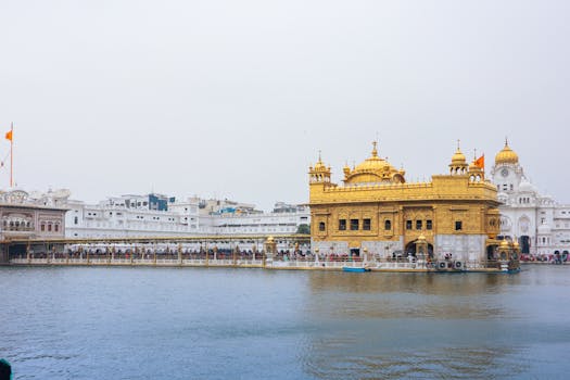 Stunning view of Golden Temple in Amritsar, India, reflected in water under a clear sky.