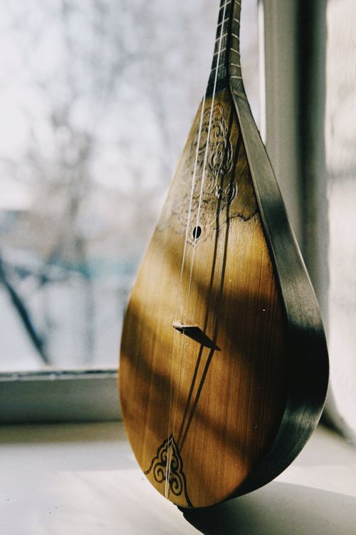 Free A wooden dombyra beautifully lit by warm sunlight near a window in Talgar, Kazakhstan. Stock Photo