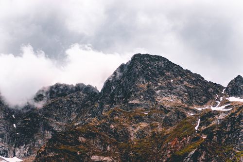Free Stunning view of rugged mountain peaks with clouds rolling over, capturing nature's grandeur. Stock Photo