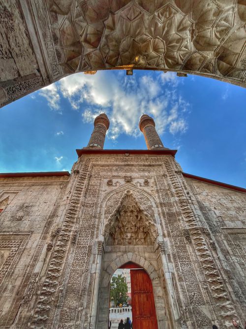 Free Stone archway with intricate carvings and two towers, framed by an open sky. Stock Photo