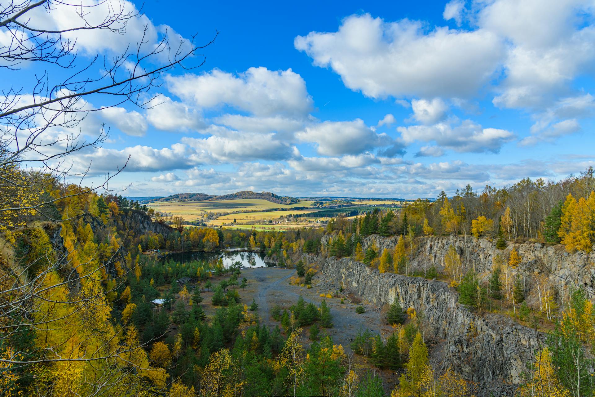 Beautiful aerial view of a quarry with autumn foliage and blue skies in Czechia.