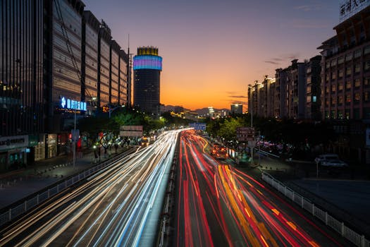 Captivating long exposure of city lights and traffic trails during a vivid sunset.