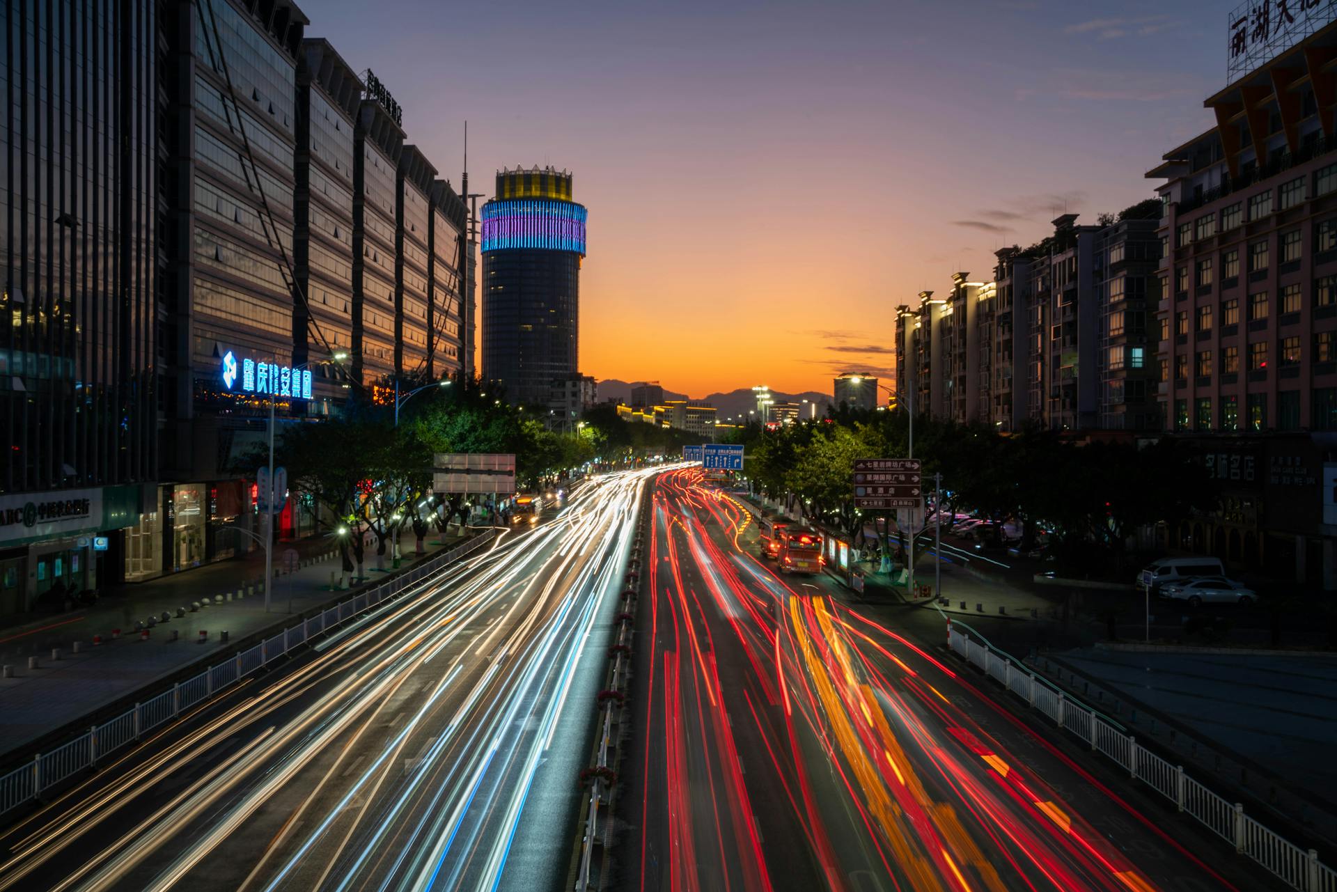 Captivating long exposure of city lights and traffic trails during a vivid sunset.