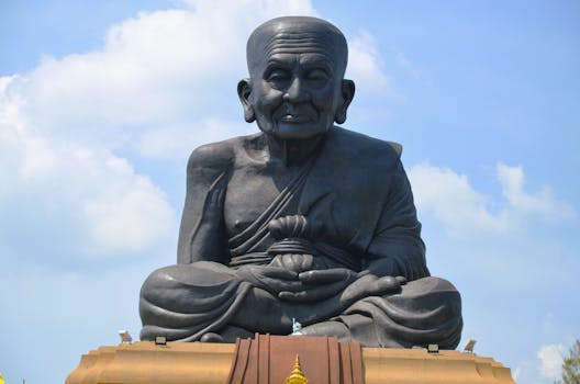 A massive Buddha statue with a serene expression against a bright blue sky.