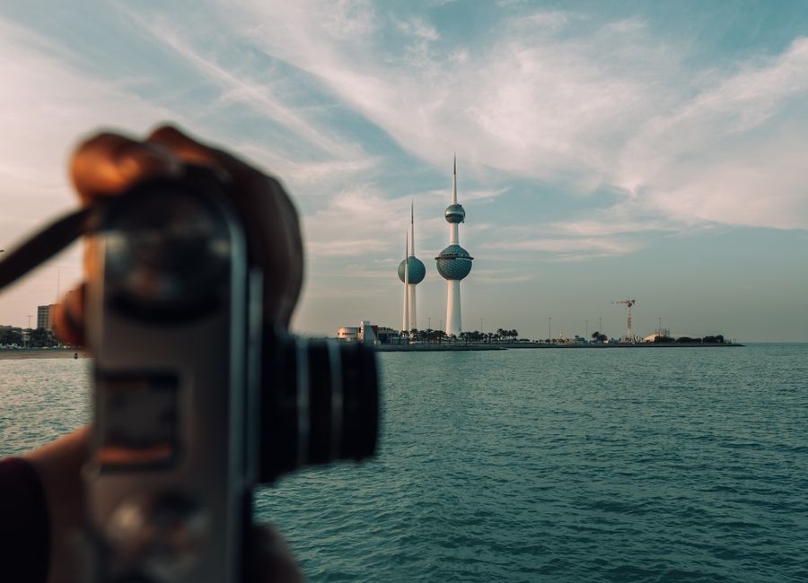 A vintage camera capturing the iconic Kuwait Towers against a serene seascape.