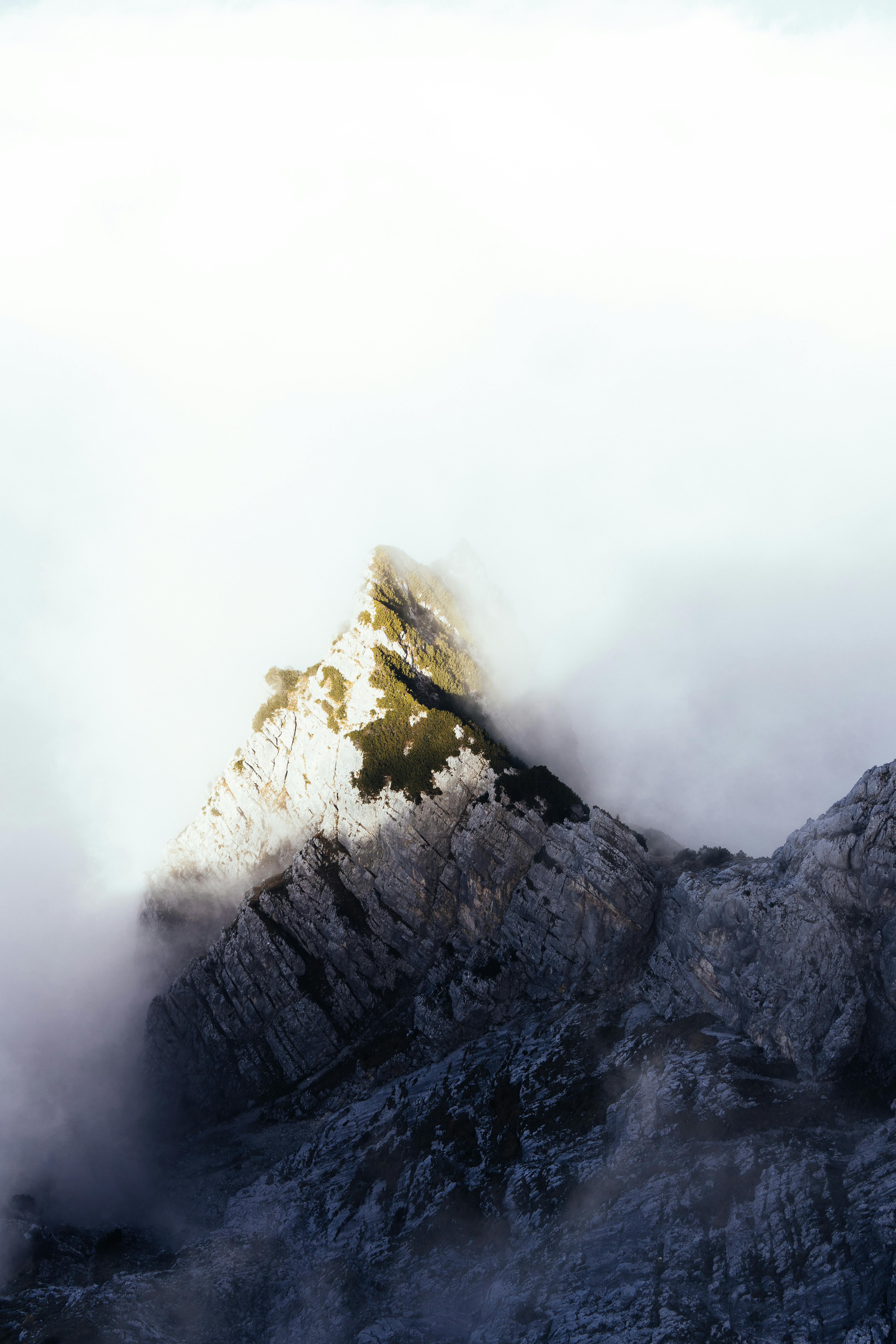 aerial shot of dense clouds creeping on the mountain peak