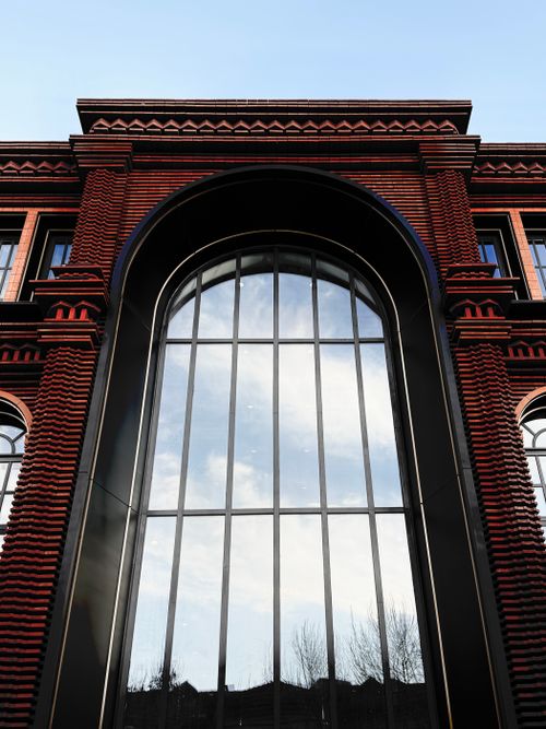 Free Arched window reflecting sky on a red brick building exterior. Stock Photo