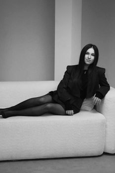 Elegant black and white portrait of a woman lounging on a sofa, exuding a classic and timeless vibe.