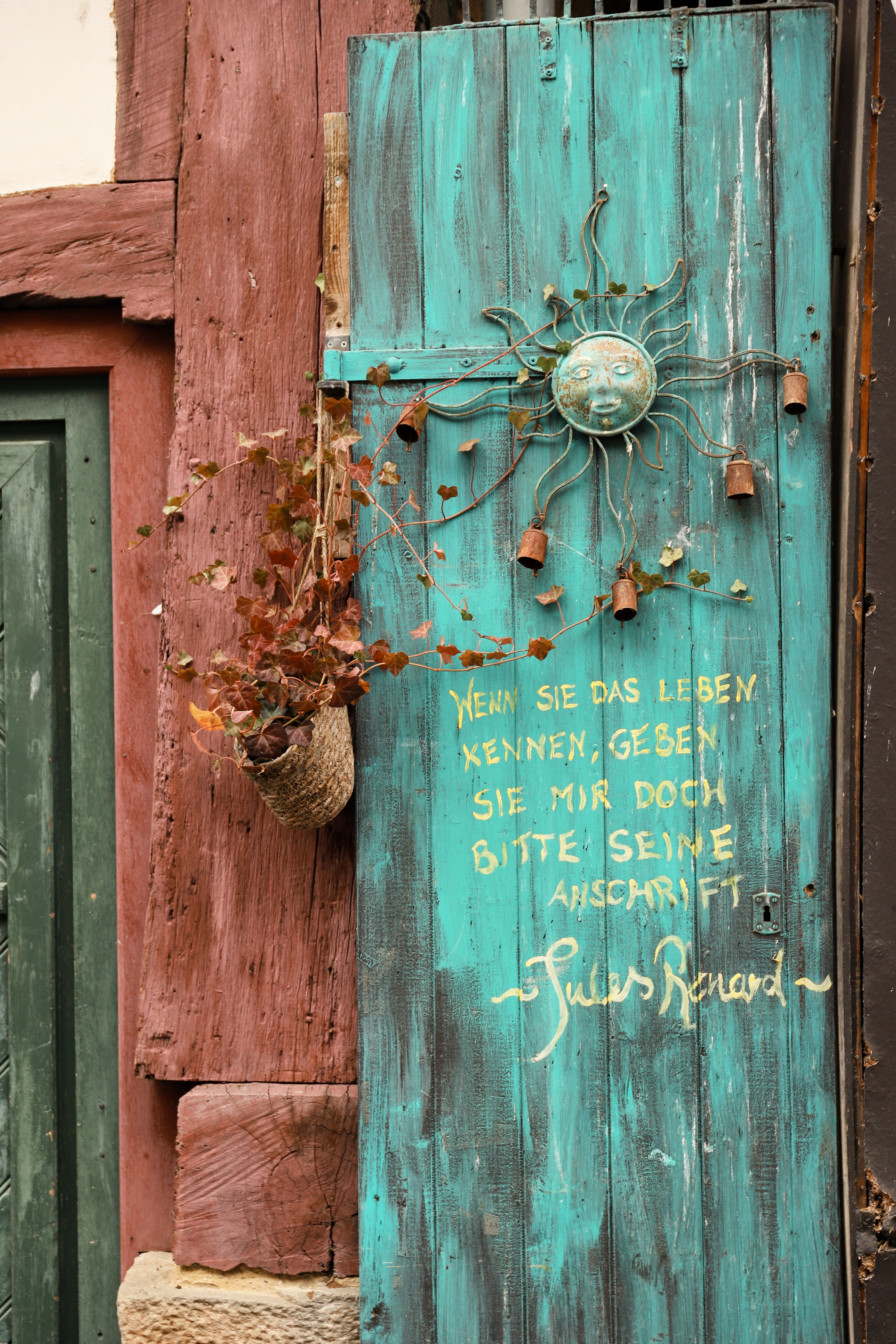 Rustic turquoise door with German proverb and sun decoration in Hann. Münden, Germany.