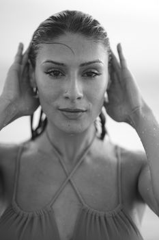 Artistic black and white portrait of a woman with wet hair, shot on a beach in Los Angeles.