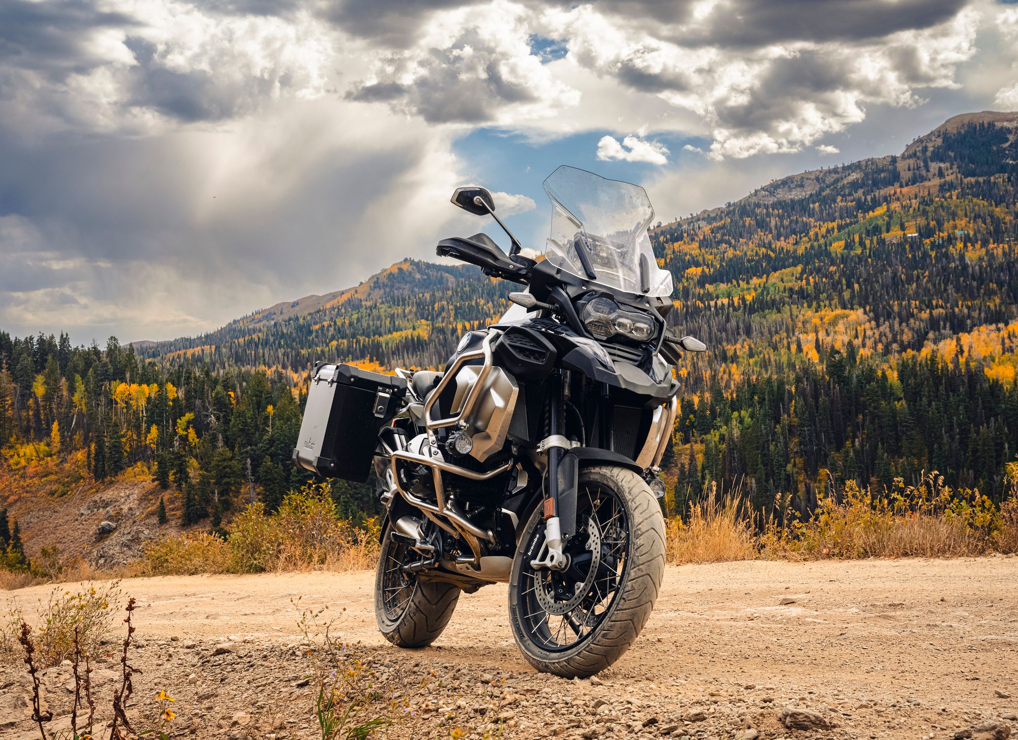 Powerful adventure motorcycle parked on a mountain road with autumn foliage.