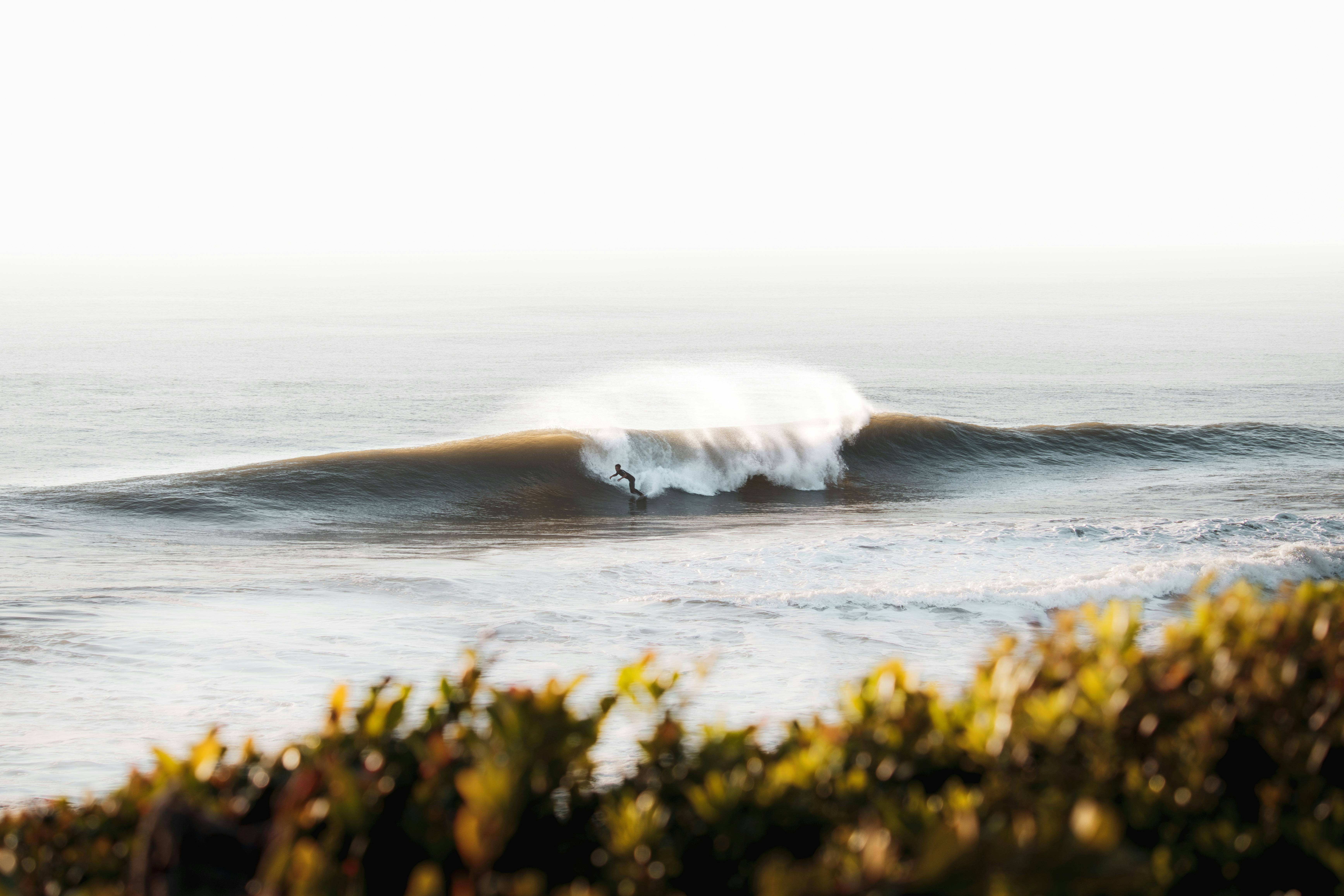 A stunning capture of a surfer embracing the ocean waves at Miyazaki, Japan, during sunset.