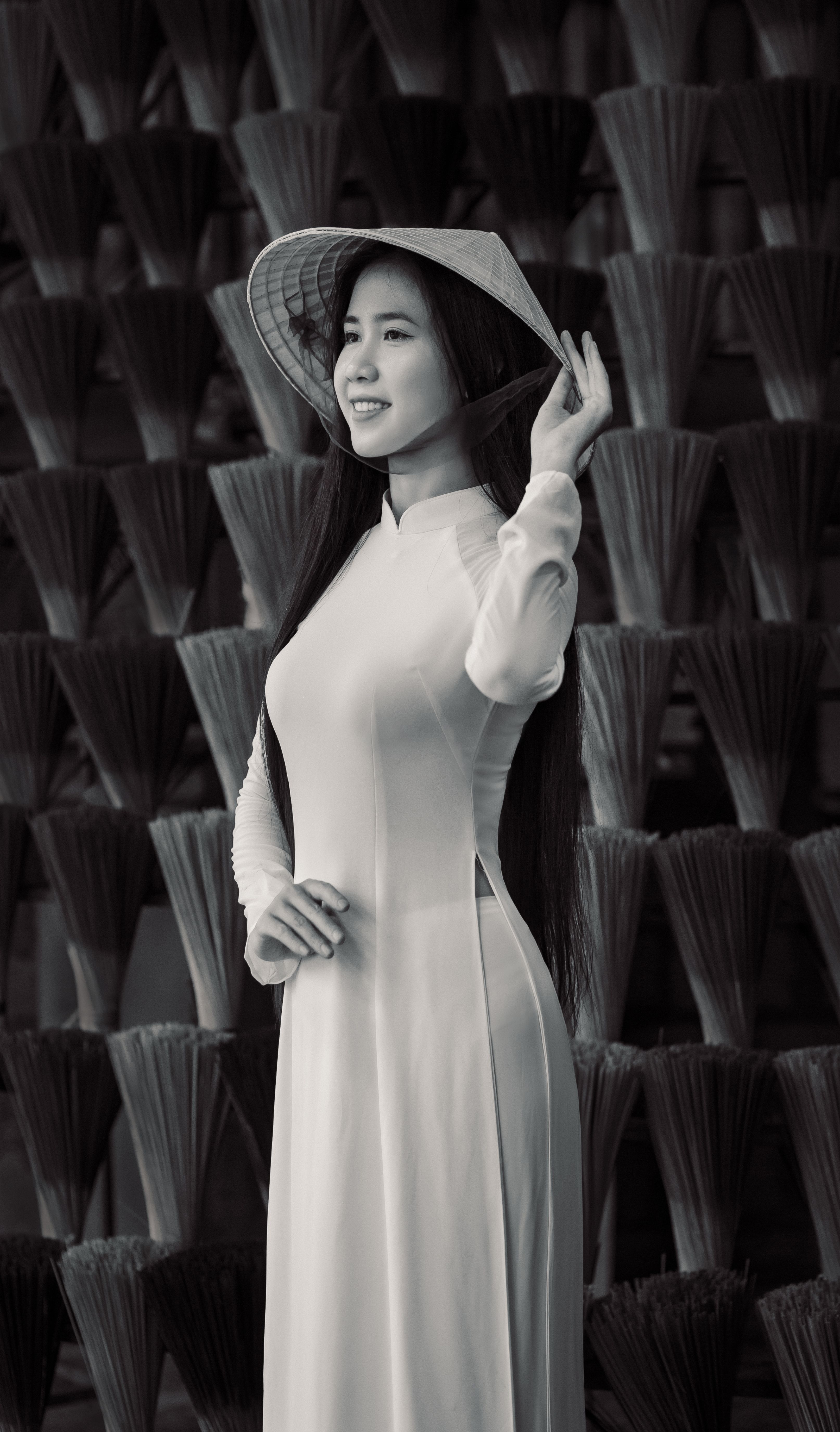 Smiling woman in a traditional Vietnamese Áo Dài and conical hat in Hội An.
