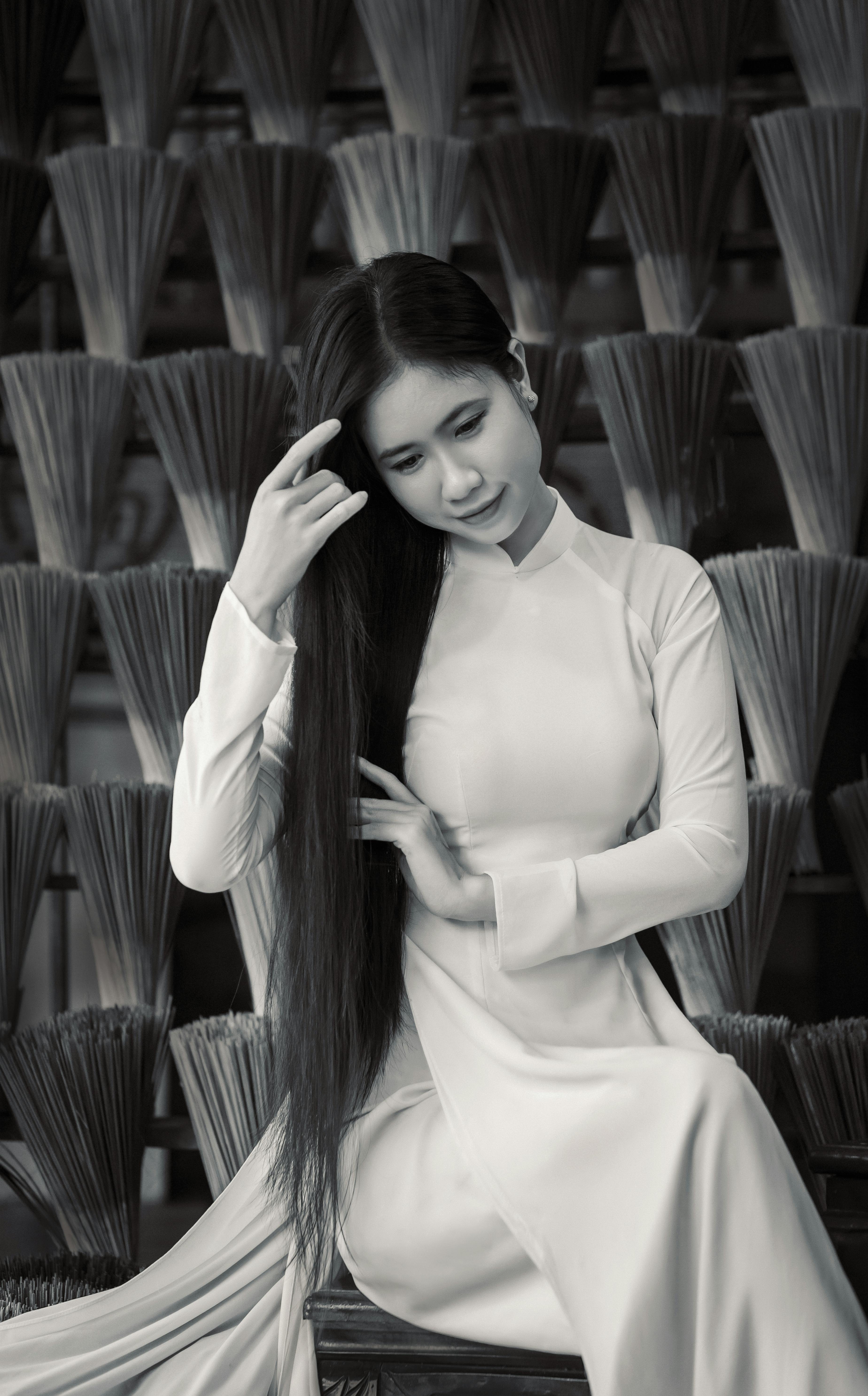 A Vietnamese woman in traditional attire posing with bundles of incense sticks, showcasing cultural heritage.
