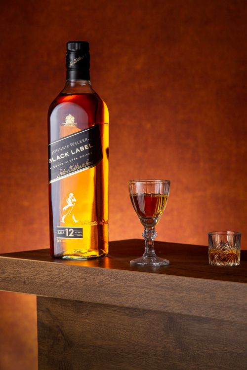 Free Elegant presentation of whiskey bottle with glasses on a wooden surface against a warm backdrop. Stock Photo