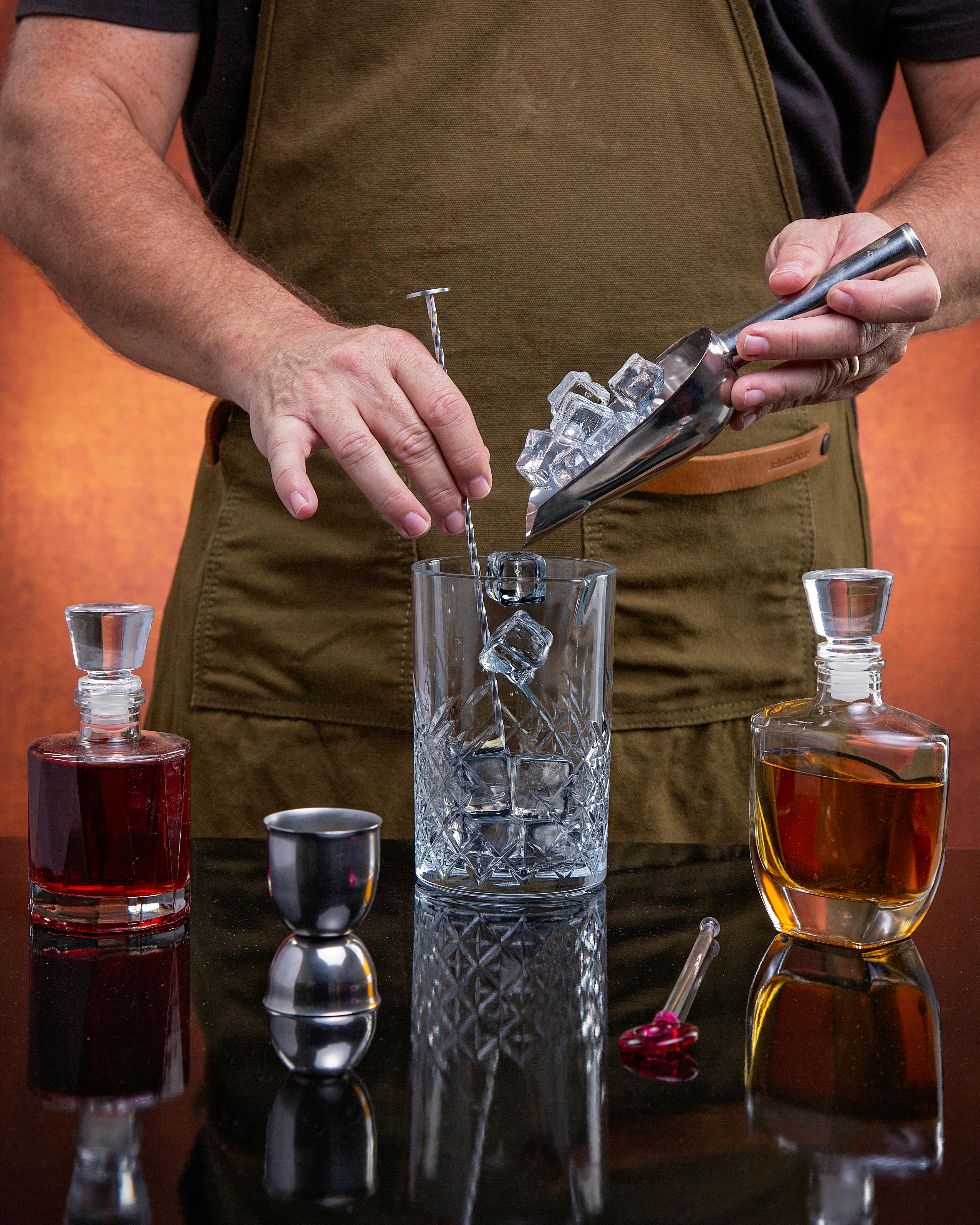 Bartender preparing cocktails with ice and mixers, showcasing mixology skills.