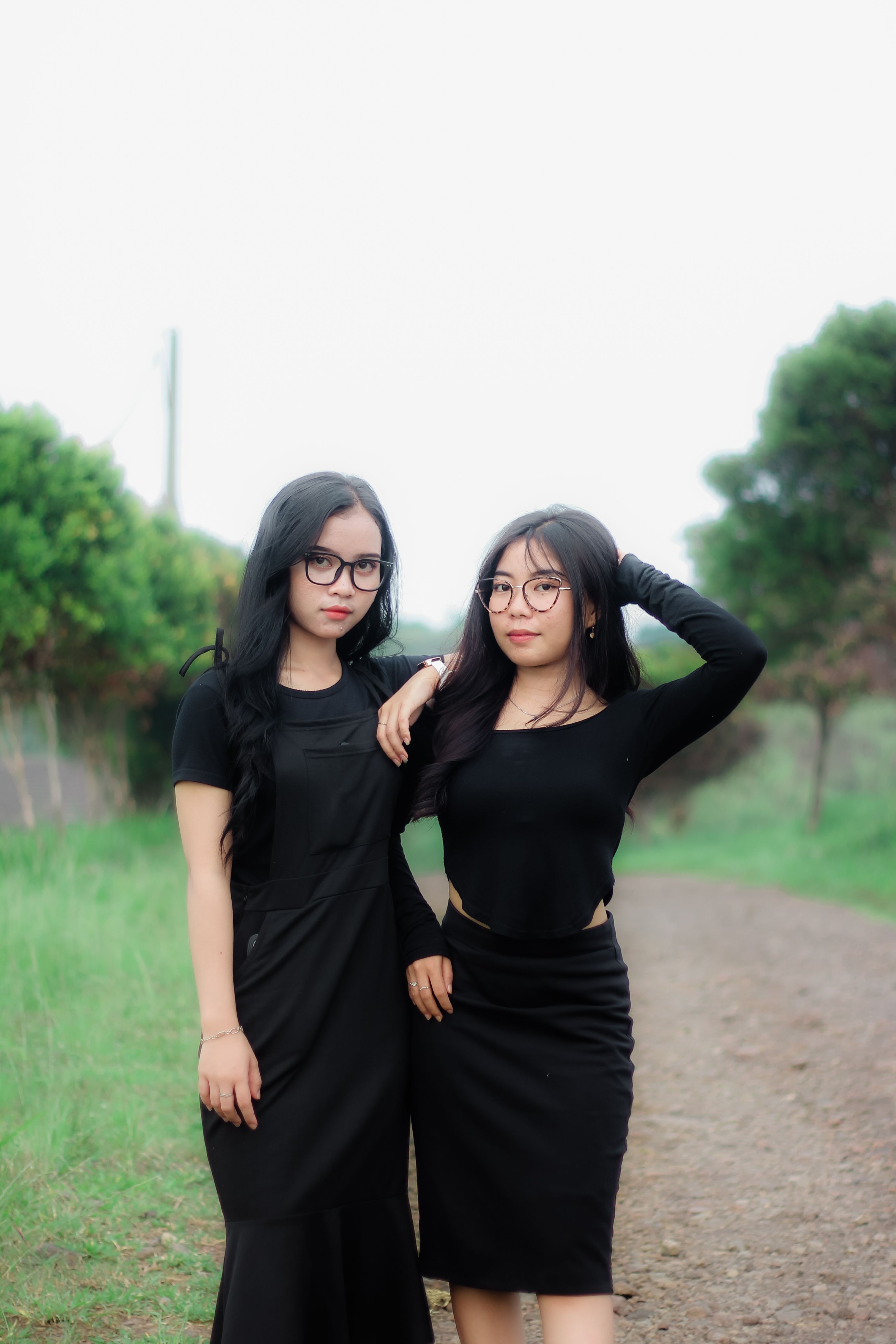 Two Women in Black Dresses Posing Outdoors · Free Stock Photo