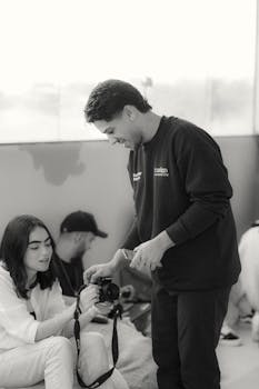 Two adults interacting over a DSLR camera in a photography class.