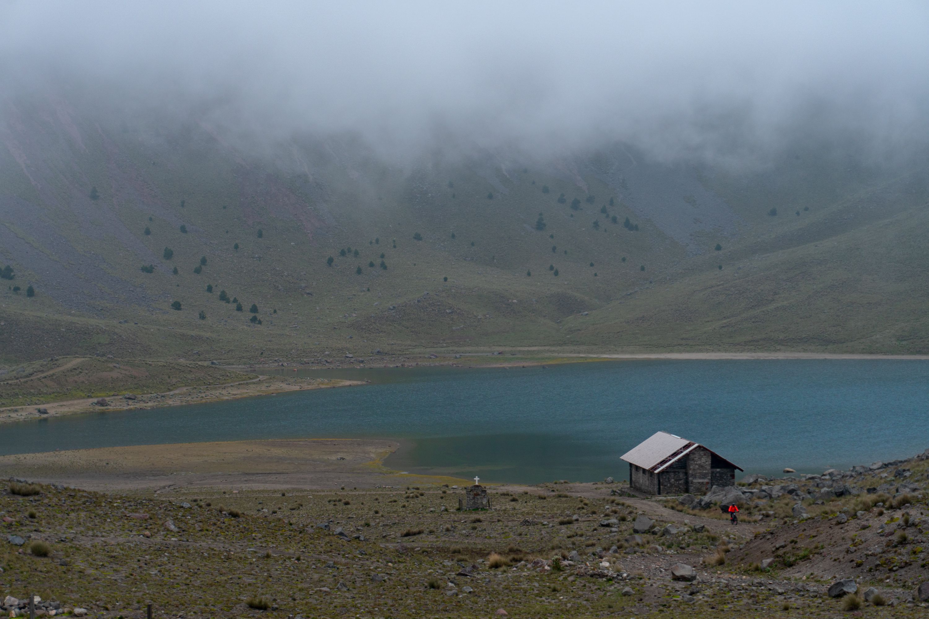 A serene landscape with a cabin by a misty lake in Nevado de Toluca, Mexico.