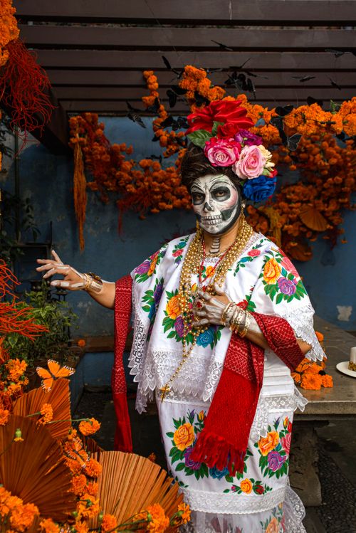 Free Vibrant portrayal of a woman in Dia de los Muertos attire with face paint and floral decorations. Stock Photo
