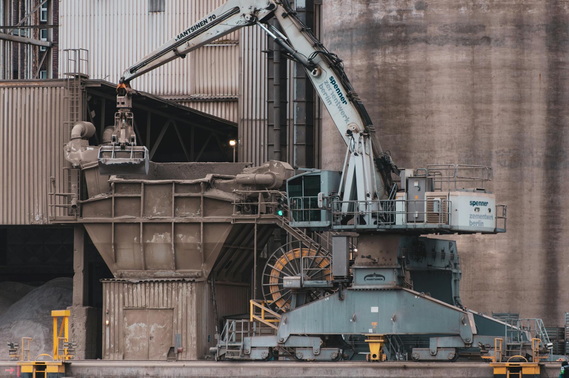 Heavy-duty excavator in operation at a cement manufacturing facility.