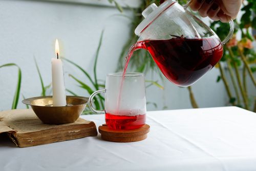 Free A cozy setting with pouring red tea, a lit candle, and a rustic book. Stock Photo