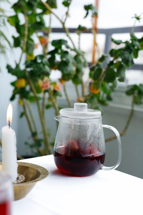 Free Cozy indoor scene with herbal tea and candlelight, surrounded by foliage. Stock Photo