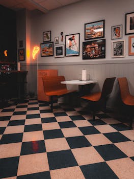 Cozy retro diner with checkered floor, orange booth seating, and neon lights.