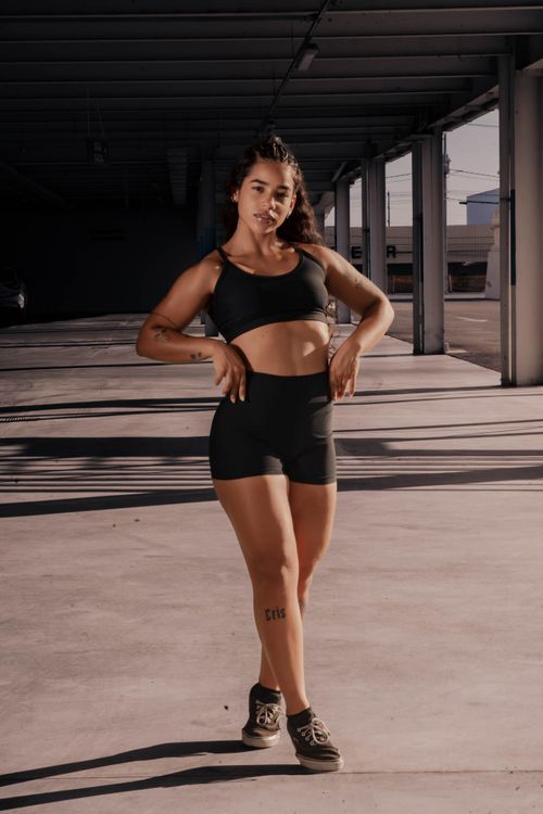 Free Fit woman in workout attire poses confidently in an industrial urban area. Stock Photo