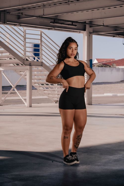 Free Young woman in workout clothing posing confidently in a sunlit urban outdoor space. Stock Photo