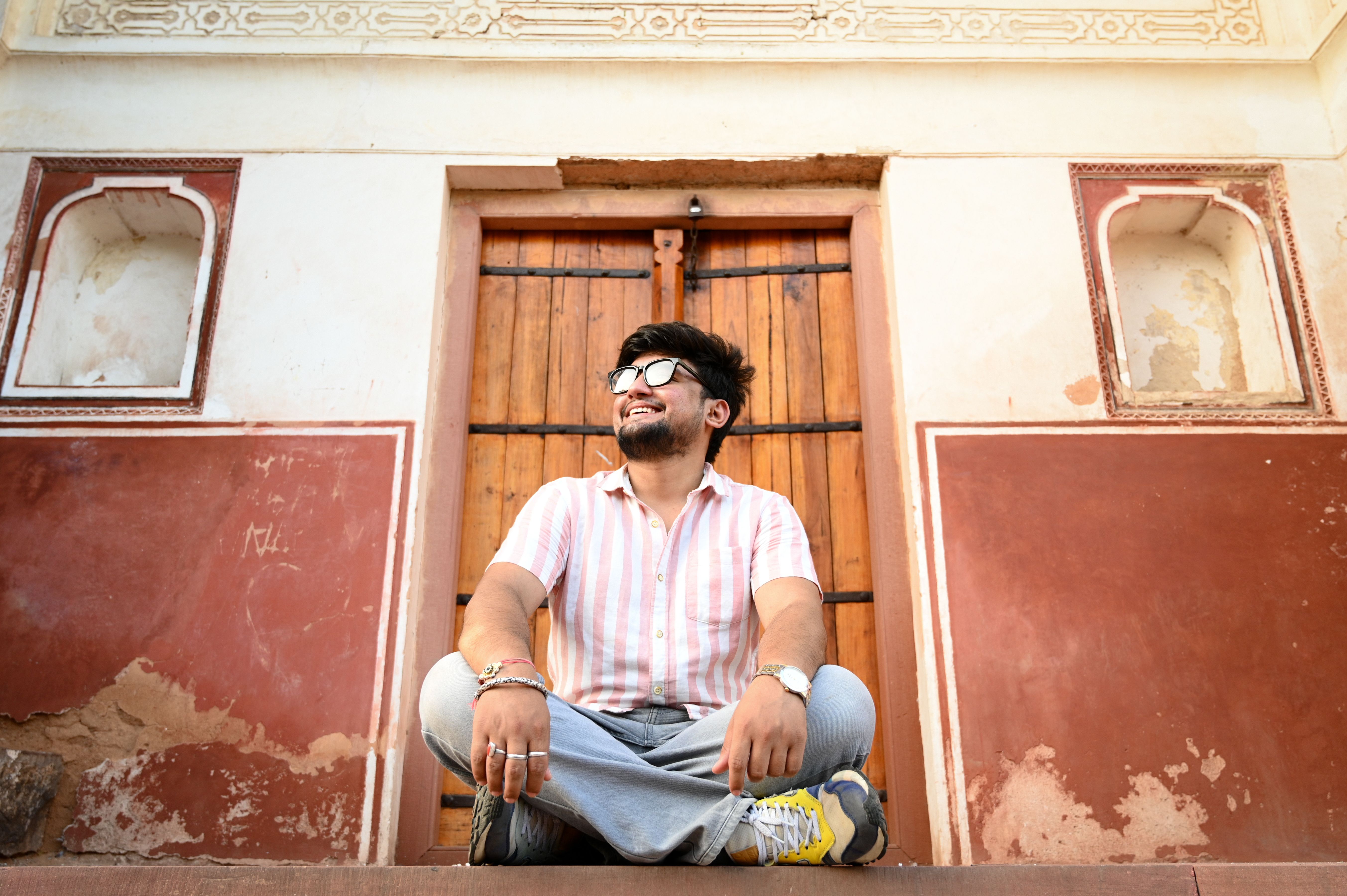 Young Man Relaxing at Historic Building Entrance · Free Stock Photo