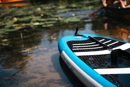 A vibrant paddleboard floating on a serene body of water with lilly pads.