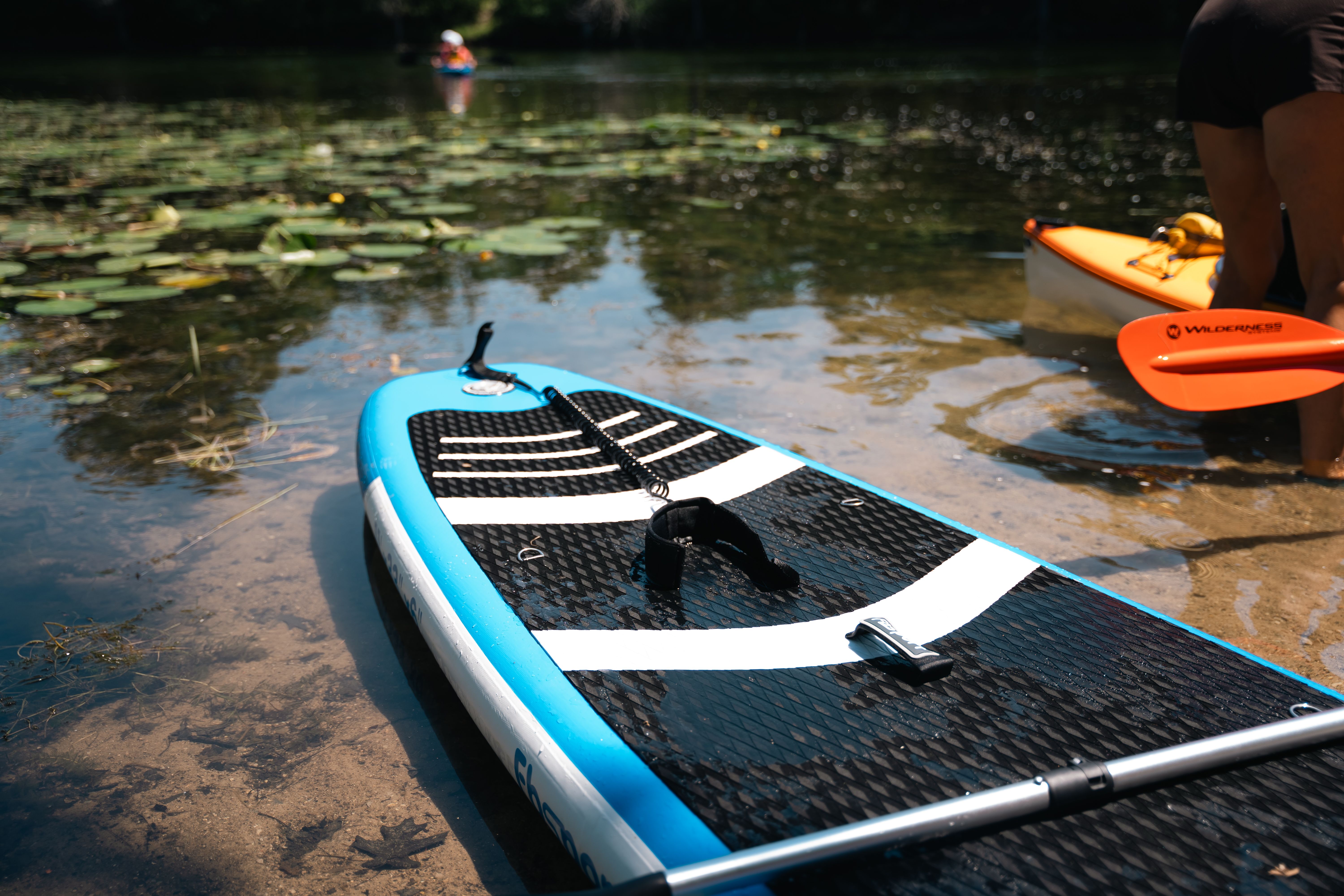 Paddleboard and kayak by a tranquil lake with water lilies, perfect for outdoor recreation.