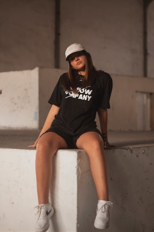 Photo of Woman in Black Top and Black Shorts Sitting Alone on Concrete Surface