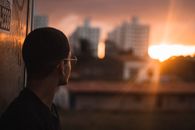 一名戴着眼镜的男子望着日落，城市景观在充满活力的夜空下映出他的轮廓